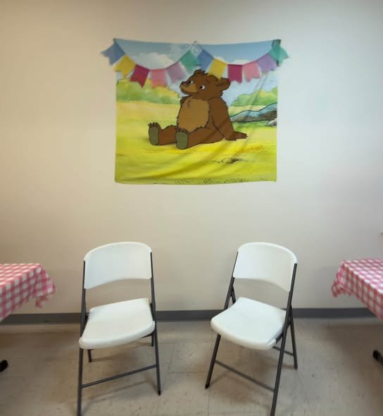 Little Bear poster with bunting and two white chairs as a photo corner