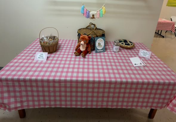 Pink gingham table with a basket, a plush bear and a small Little Bear banner