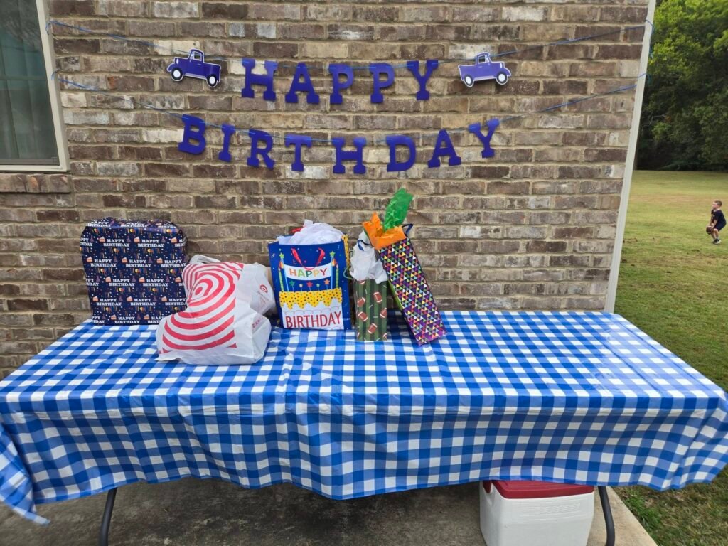 Gift table with a blue gingham cloth and a Happy Birthday banner