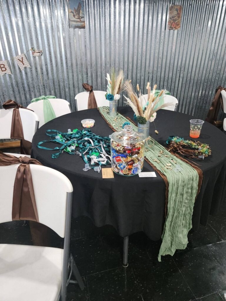 Black round table with a green runner and a dried grass centerpiece