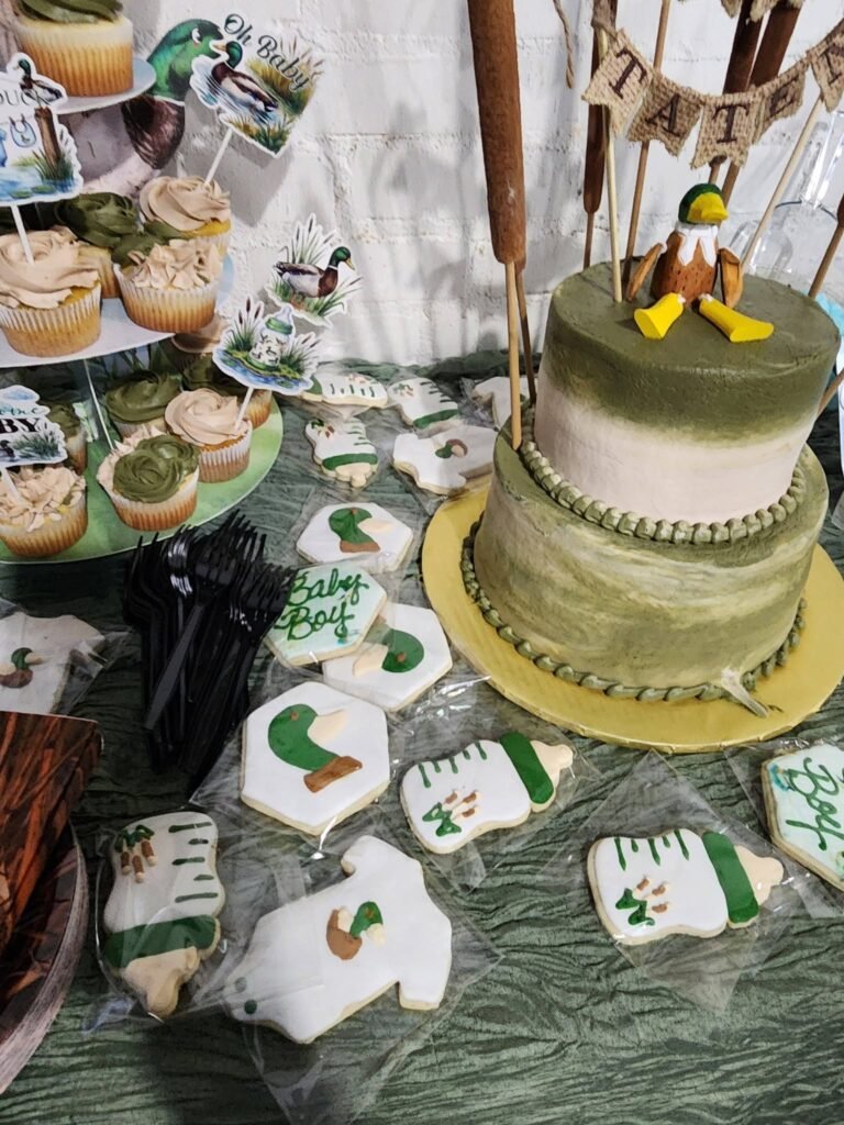 Duck baby shower dessert table with cake, cupcakes and onesie cookies