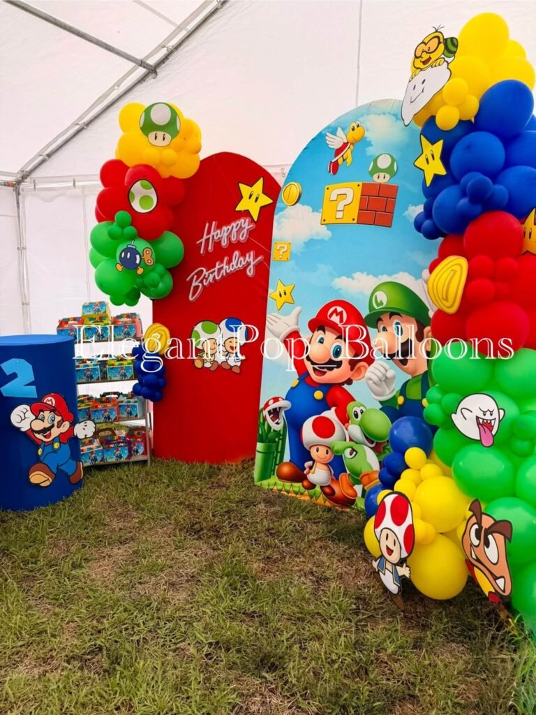 Mario party backdrop with a red arch, character cutouts and balloons in a tent