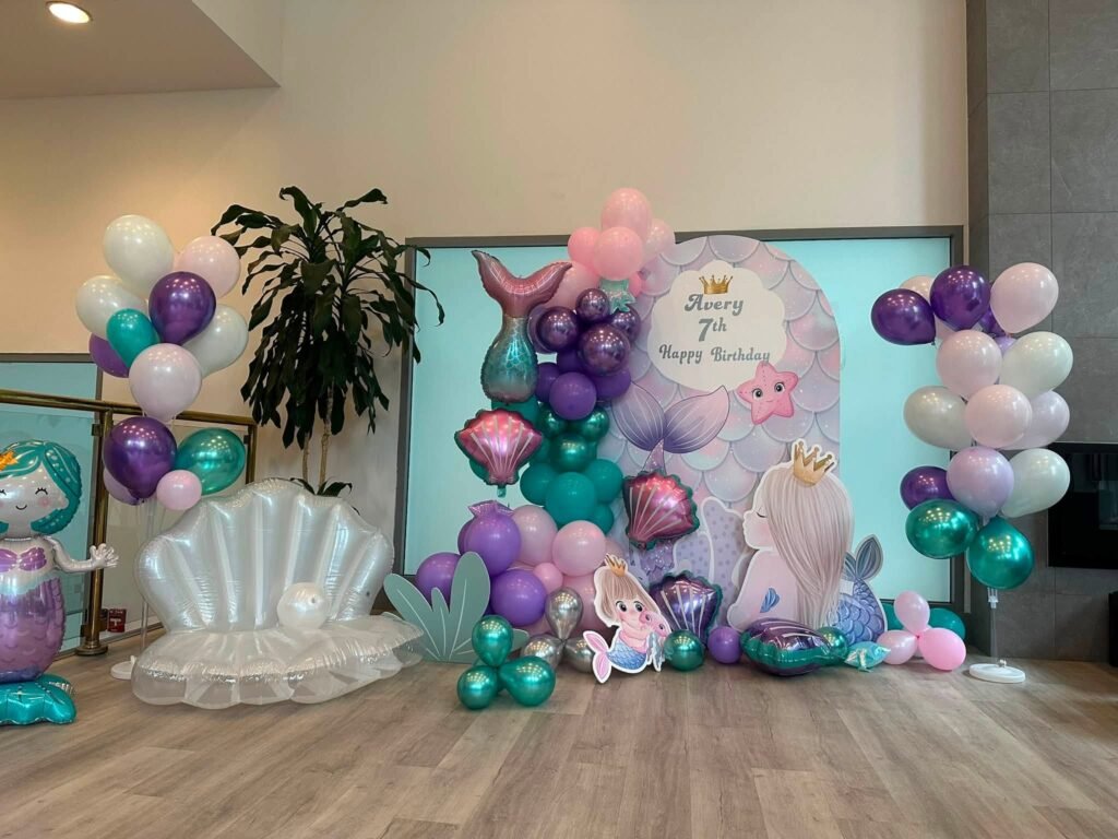 Teal, purple and pink balloon wall with a big shell chair