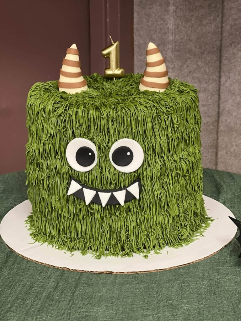 Green buttercream fur cake with big eyes, horns and a number one