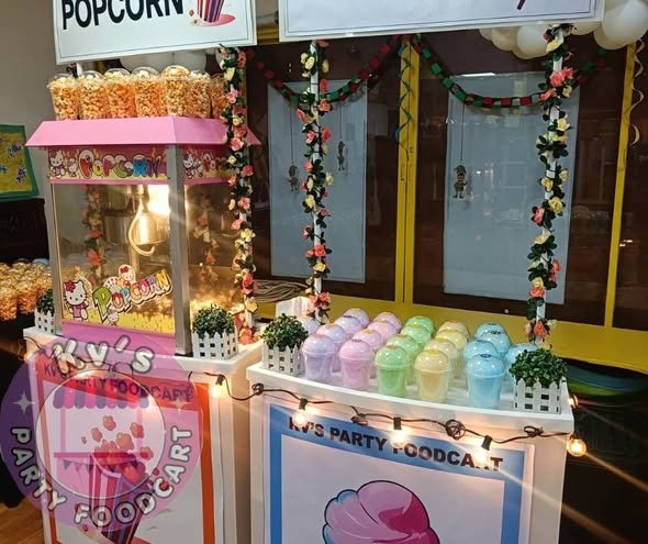 Popcorn station with a pink popcorn machine, flower garland and pastel cups