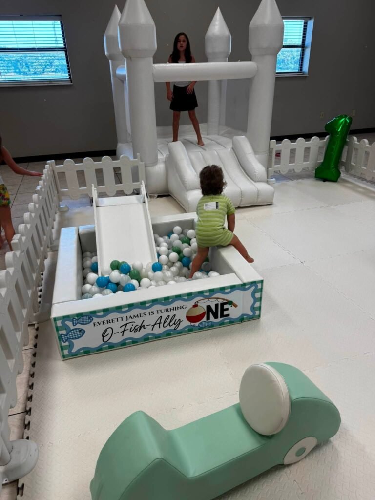 White soft play pen with a slide and an O-fish-ally One sign