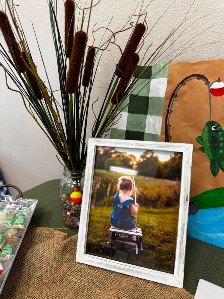 Cattails in a vase with a framed baby photo and a fish decor