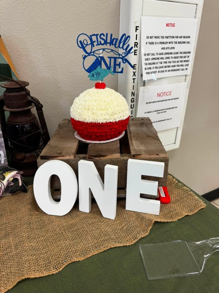 Red and white bobber smash cake on white ONE letters next to a lantern