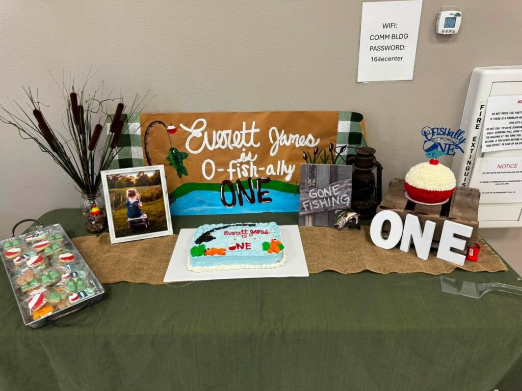 Fishing birthday dessert table with a wood name sign, cattails and ONE letters