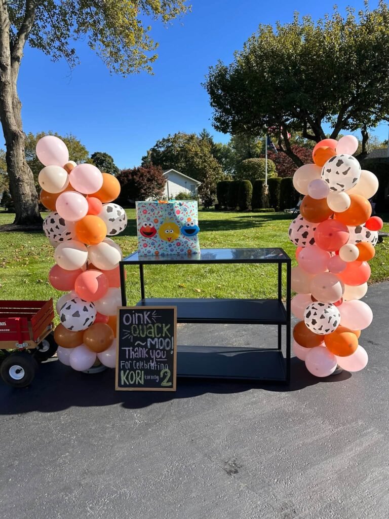 Cow print and orange balloon columns by a little wagon