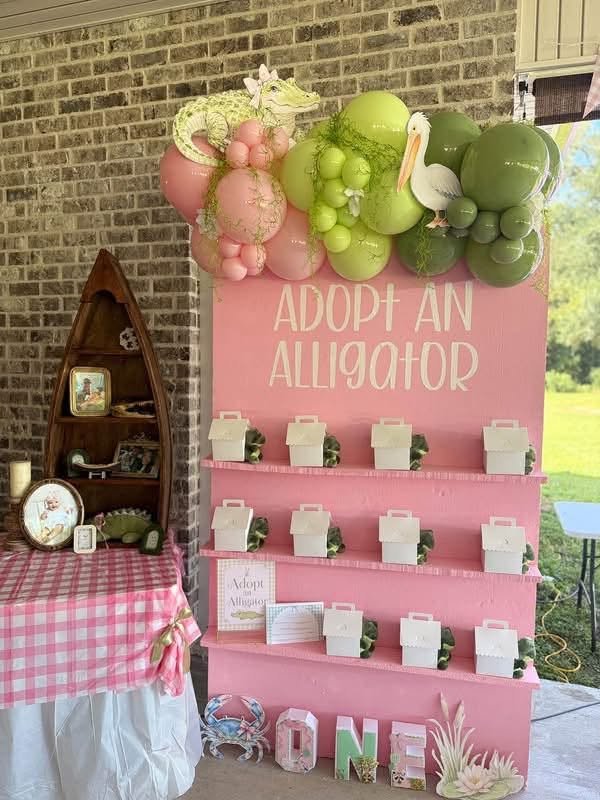 Adopt an Alligator favor wall with pink shelves, balloons and a pelican cutout