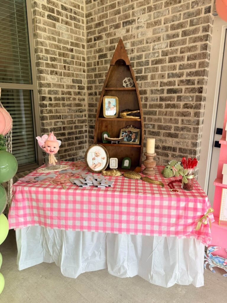 Pink gingham table with a wood boat shelf, photos and red flowers