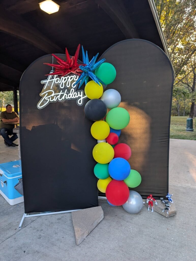 Black arch panel with a Happy Birthday sign and a colorful balloon column