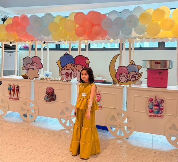 Girl by pastel food carts with a balloon canopy and Little Twin Stars art
