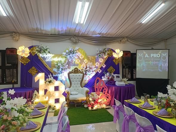Purple and gold debut stage with a light up 18 sign, throne chair and guest tables