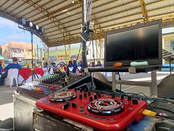 DJ booth with a red mixer, laptop and screen at a party