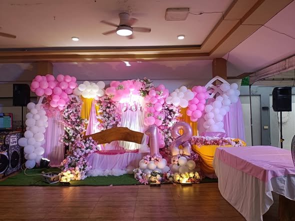 Pink floral party stage with balloons, a sofa and lights