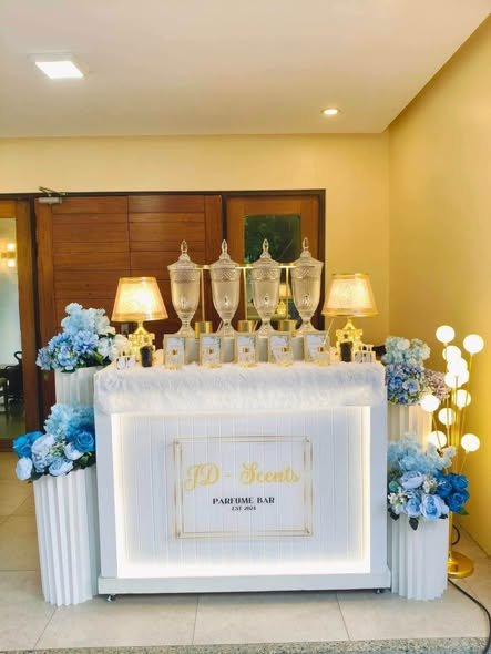 White perfume bar counter with glass scent jars, lamps and blue flower columns