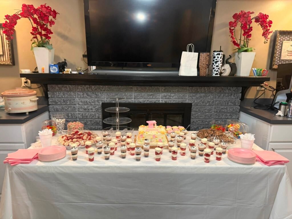 Pink graduation dessert table with red orchids in front of a fireplace