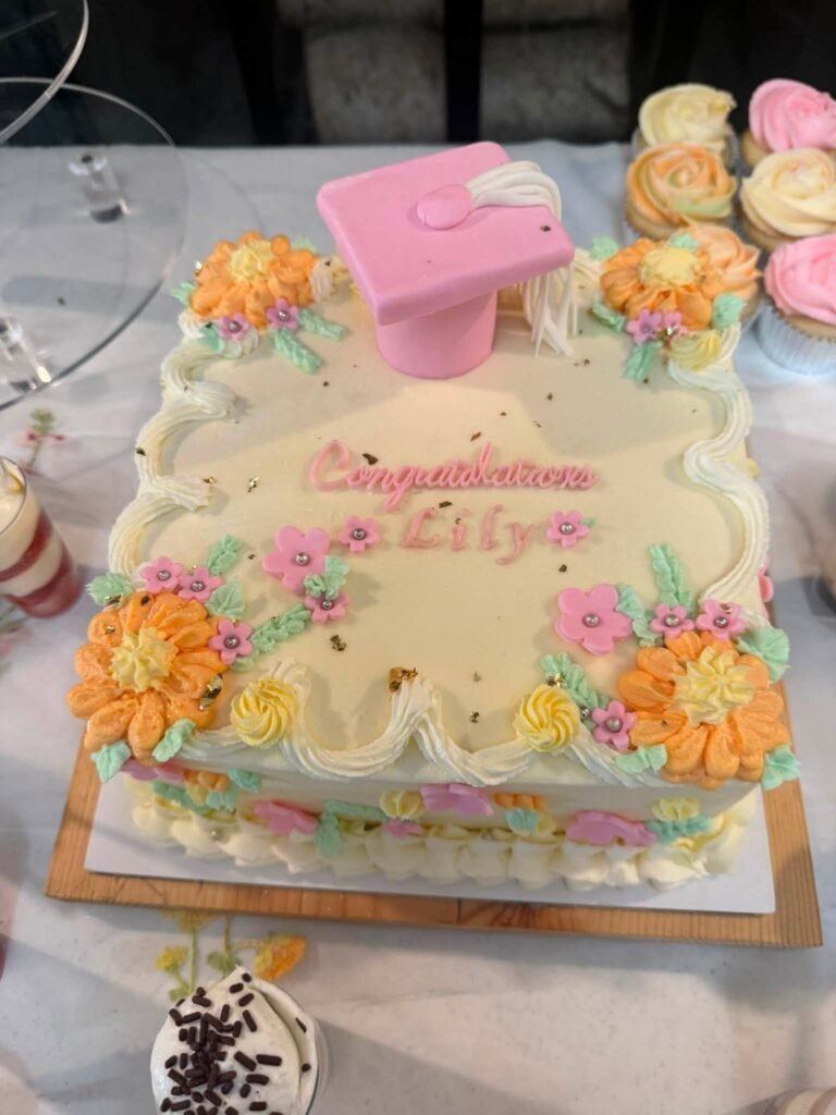 Graduation sheet cake with a pink grad cap and orange and pink buttercream flowers