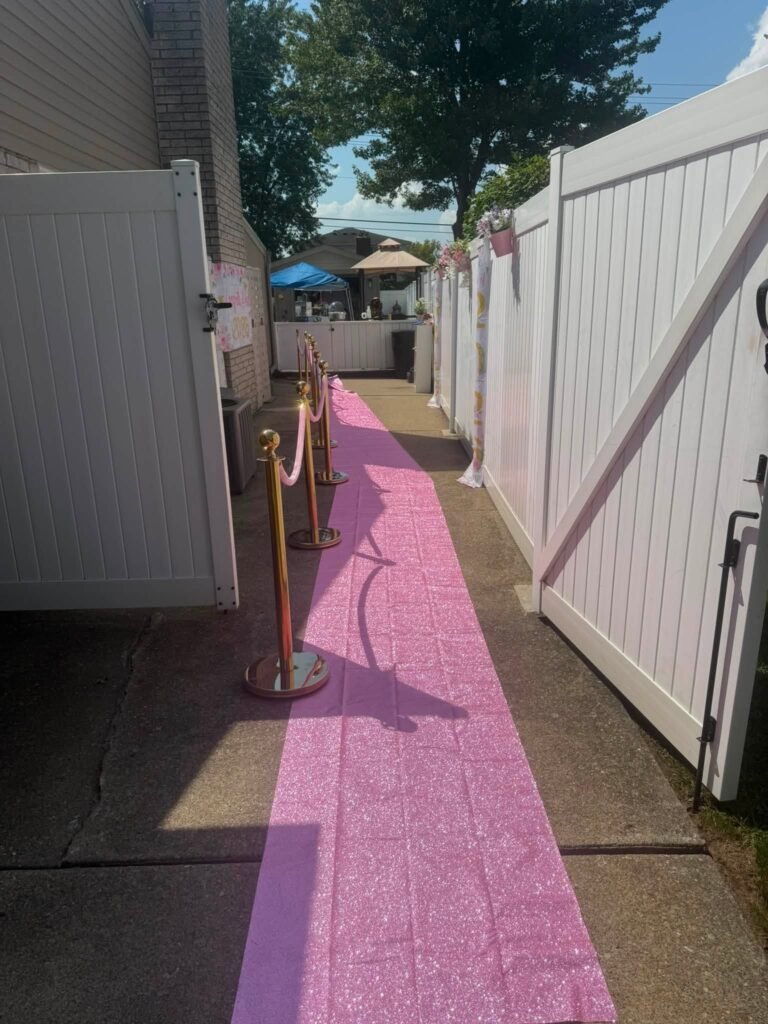 Pink carpet walkway with gold stanchions leading into the backyard