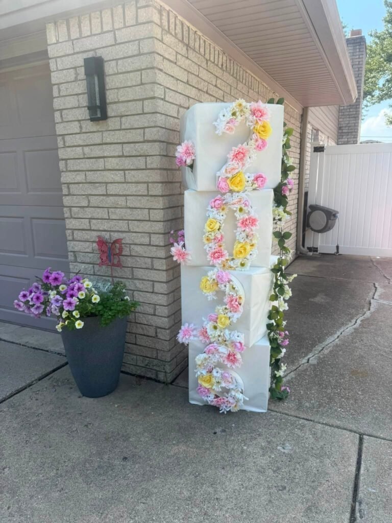 Flower wrapped column with pink and yellow blooms by a garage