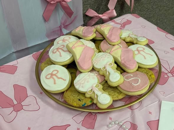 Bow shaped sugar cookies with pink and green icing on a gold plate