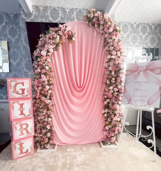 Pink draped baby shower backdrop with a flower arch and GIRL letter blocks