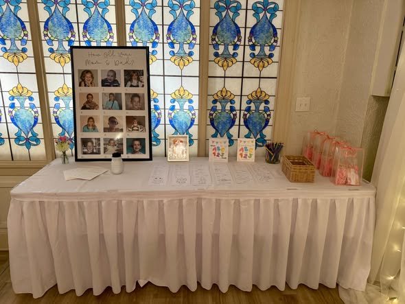 Baby shower table with framed baby photos and a pink gift bag