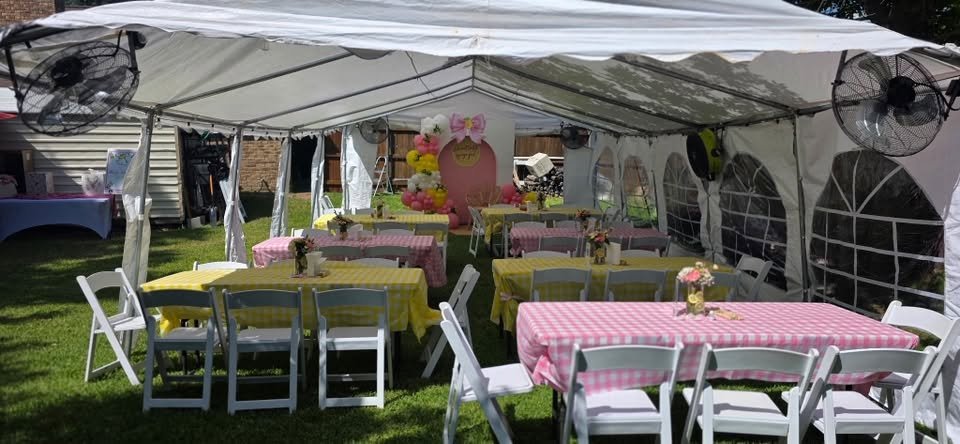 Wide view of a baby shower tent with pink and yellow tables