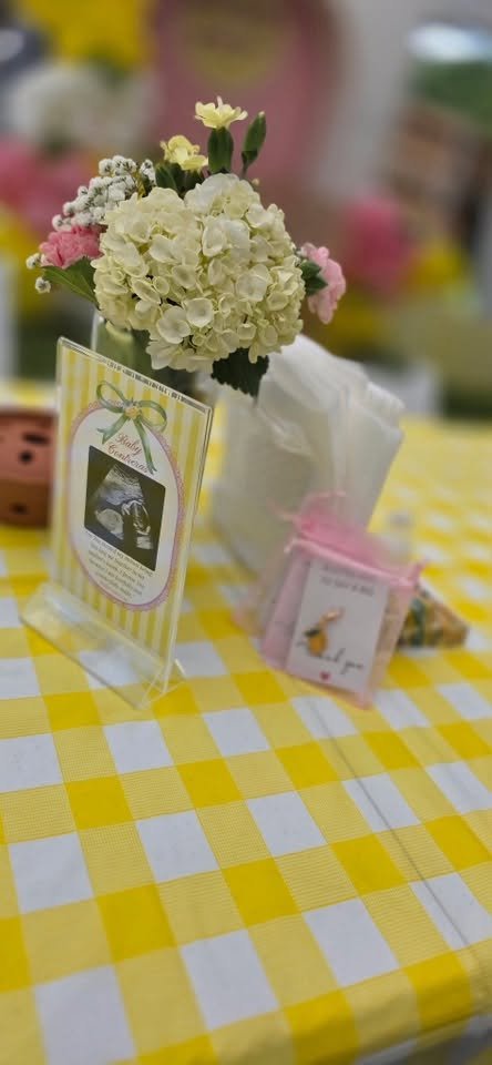 White flower centerpiece with a framed photo on a yellow gingham table
