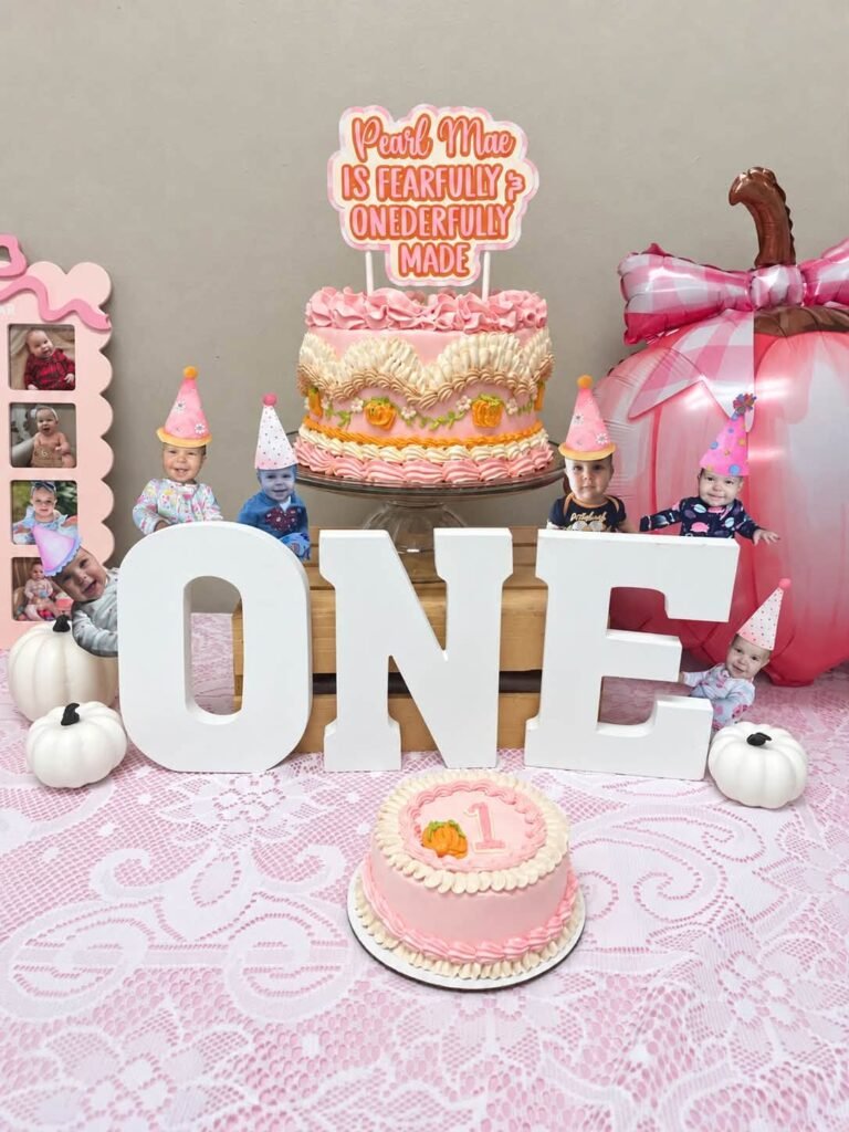 Tall pink pumpkin birthday cake behind white ONE letters with a pink smash cake in front