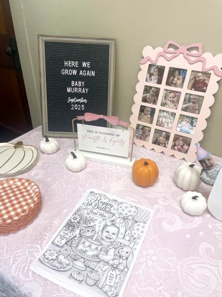 Letter board sign and a monthly photo frame with pink bows on a pumpkin table