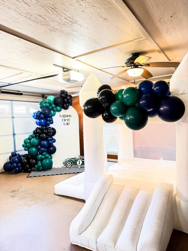 Green, navy and black balloon garland over a white soft play area in a garage
