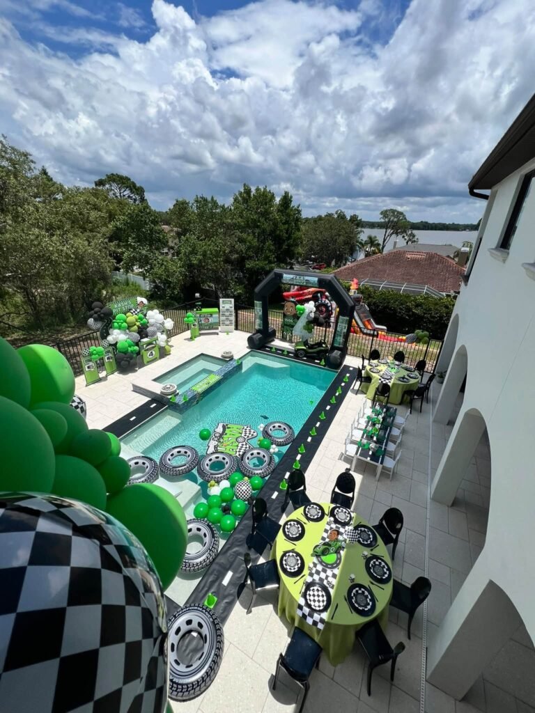 Wide view of a race car pool party with balloons and tables