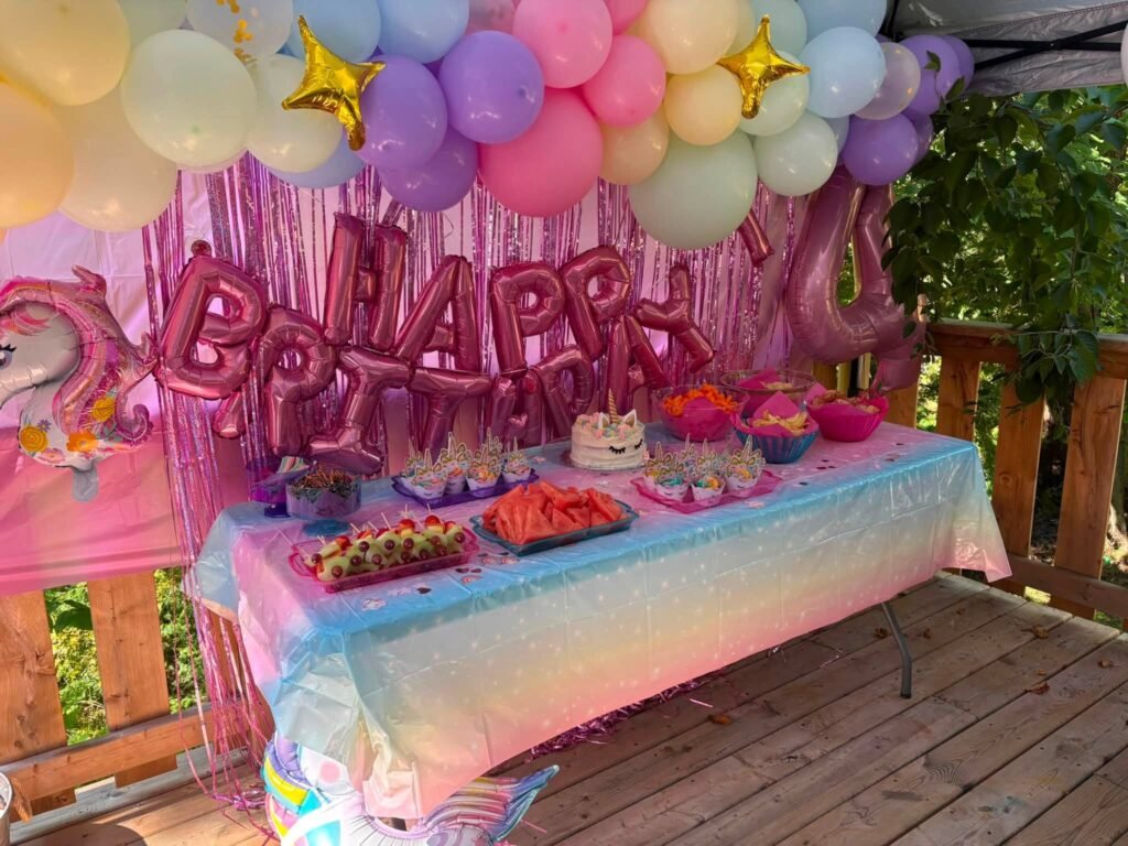 Pink foil birthday balloons above a colorful party table