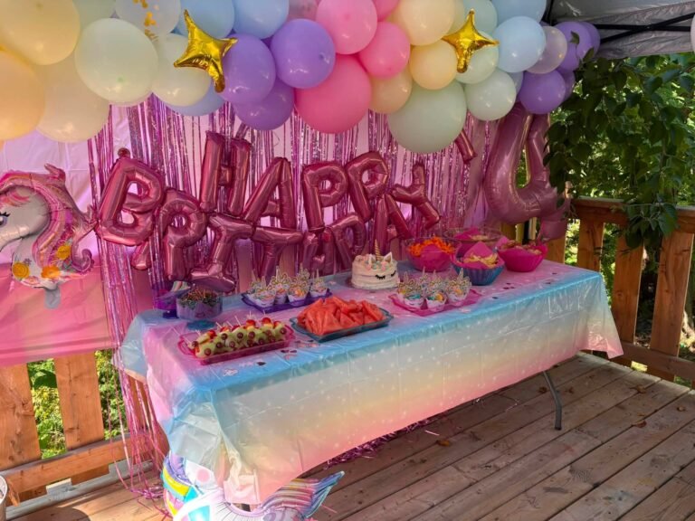 Pink foil birthday balloons above a colorful party table
