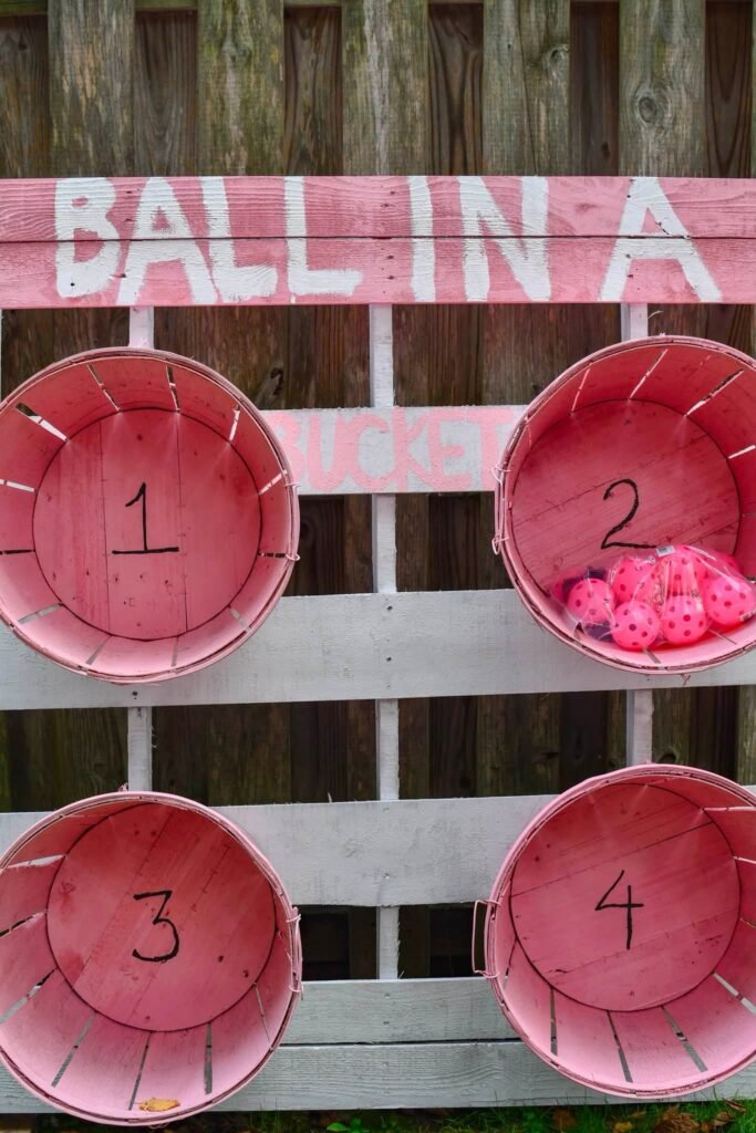 Ball toss game with numbered pink bowls on a board