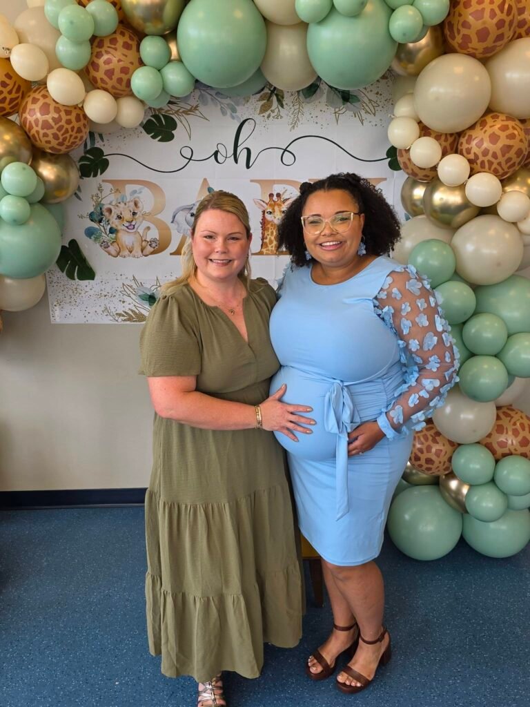 Mom to be at a safari baby shower backdrop with sage, cream and leopard print balloons
