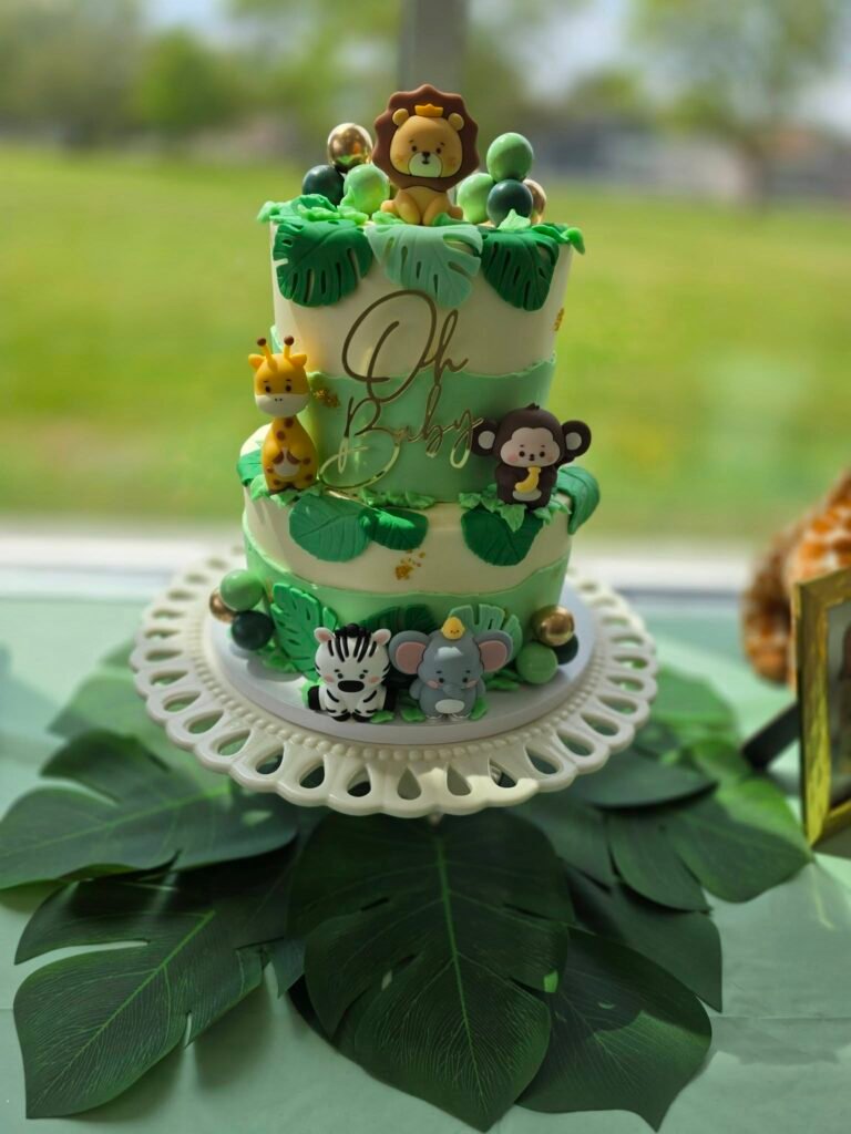 Two tier safari baby shower cake with jungle animals and a leaf base