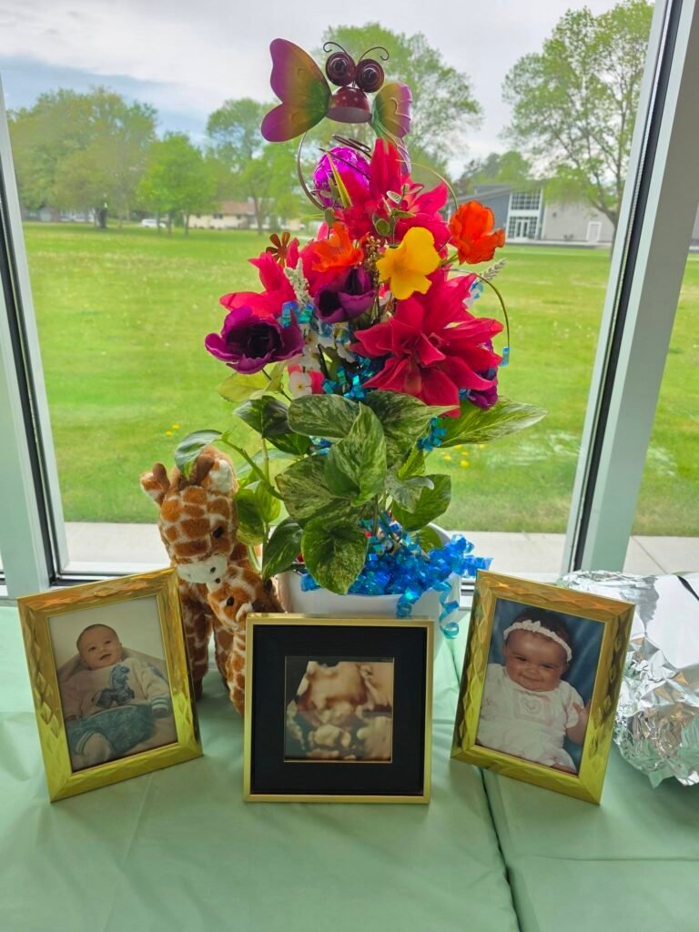 Bright flower centerpiece with framed baby photos on a sage table