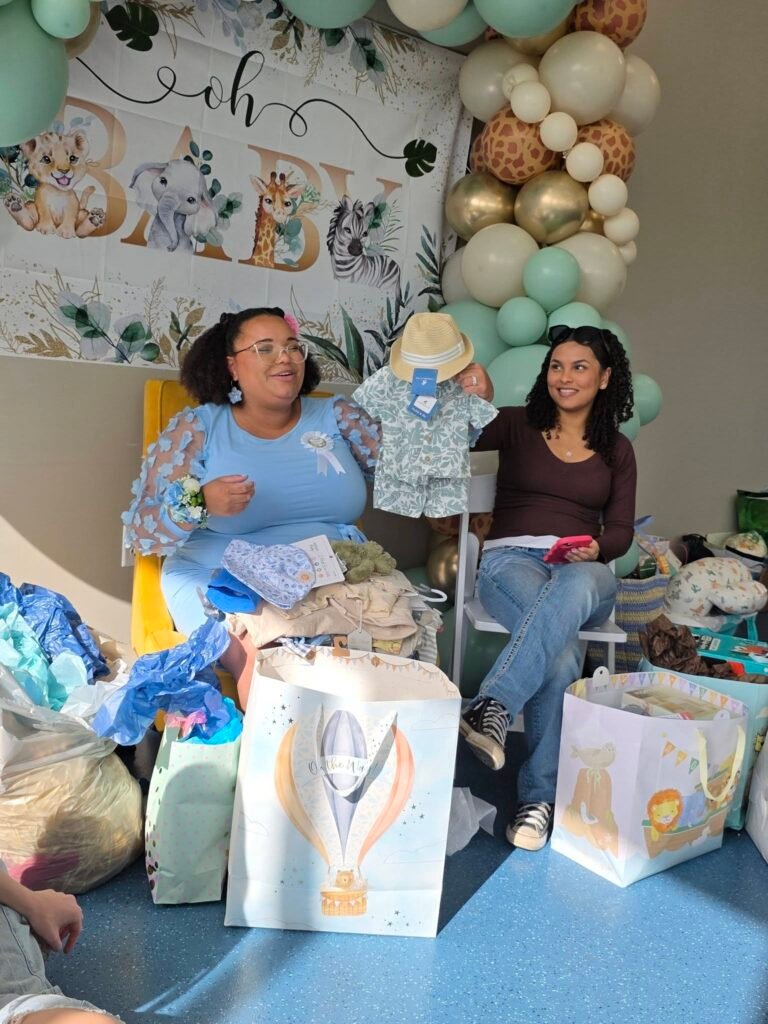 Mom to be opening baby gifts in front of the safari backdrop