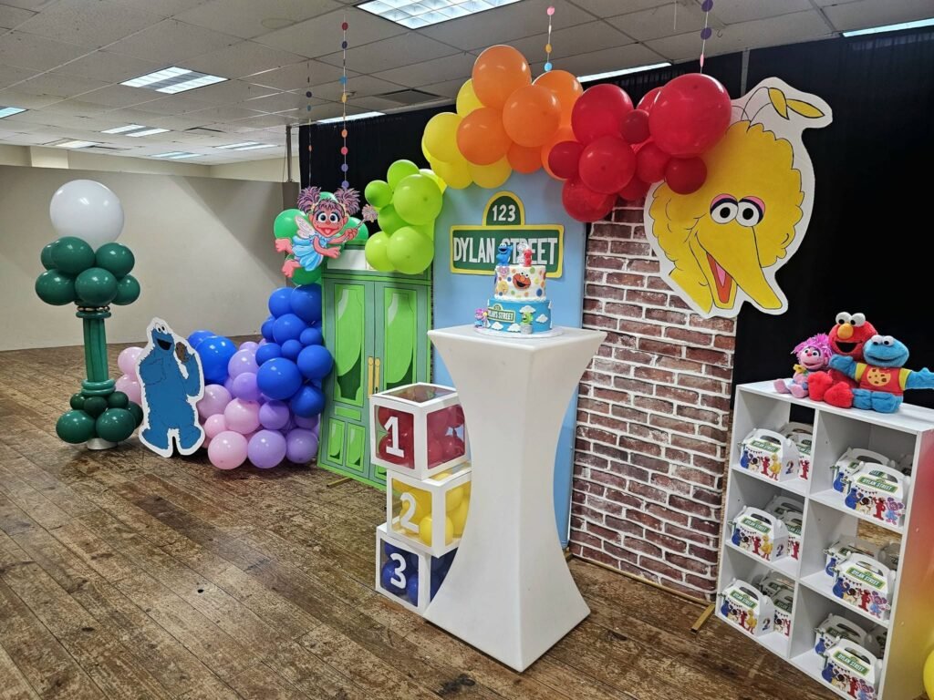 Sesame Street 2nd birthday backdrop with a brick wall, Big Bird, rainbow balloons and a favor shelf