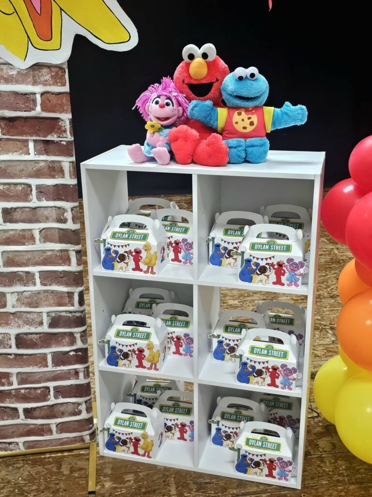 White cube shelf filled with Sesame Street favor boxes and plush characters on top