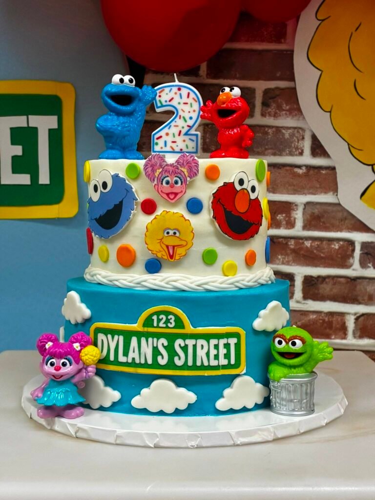 Two tier Sesame Street birthday cake with Elmo, Cookie Monster, Abby and a street sign