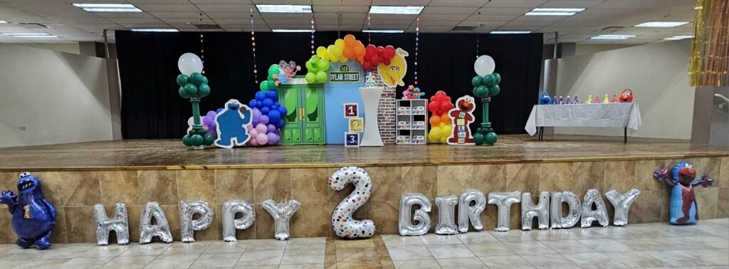 Happy 2 Birthday letter balloons on a stage with Sesame Street balloon decor