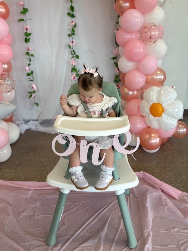 High chair with a pink balloon garland