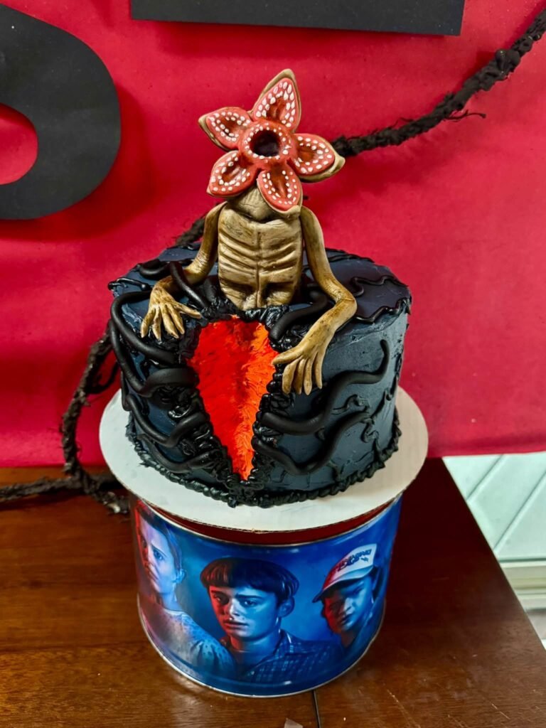 Black cake with a Demogorgon topper on a printed base