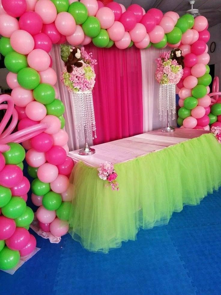 Pink and green balloon arch over a table with a lime green tulle skirt