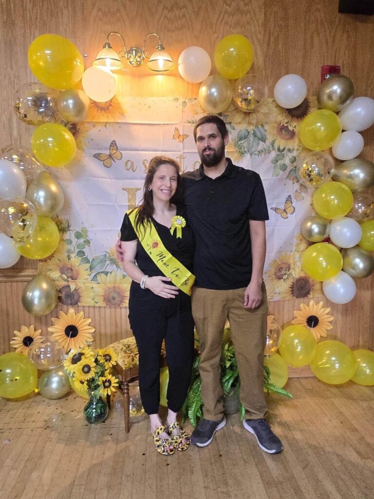 Parents to be posing at the sunflower balloon backdrop